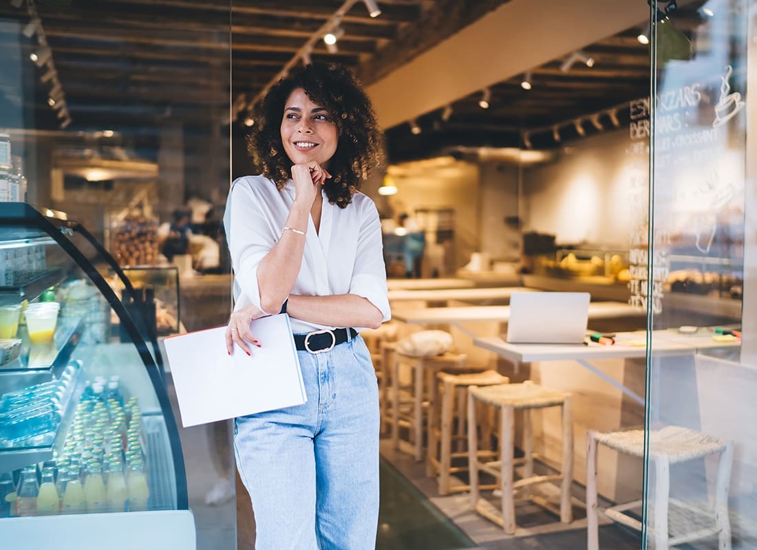 Business Insurance - Portrait of a Young Restaurant Owner Standing in the Front Entrance of her Cafe with Papers in her Hands