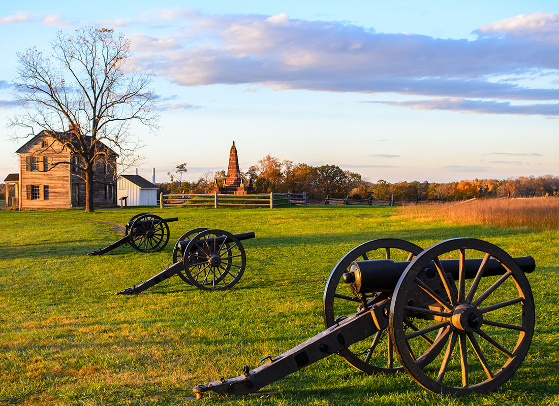 Contact - View of Historic Cannons on a Green Field in a Park in Virginia at Sunset