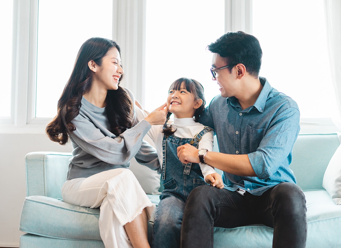 Read Our Reviews - Portrait of a Cheerful Asian Family with a Young Daughter Sitting on the Sofa in a Bright Living Room